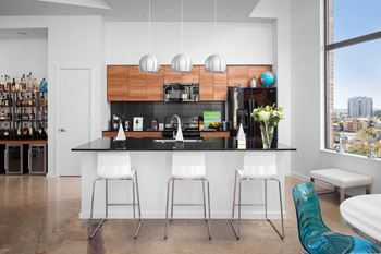 a kitchen with a black counter top and white stools